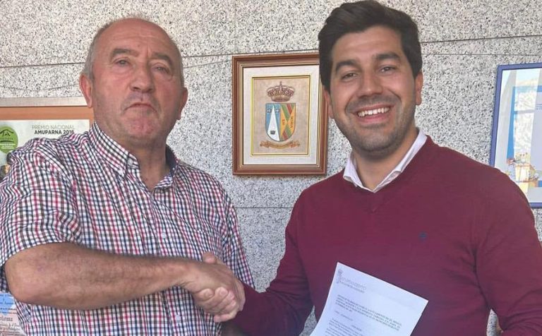 Sergio Yunquera - se dan la mano sonriendo, uno recibe un documento, sugiriendo un acuerdo o reconocimiento formal.